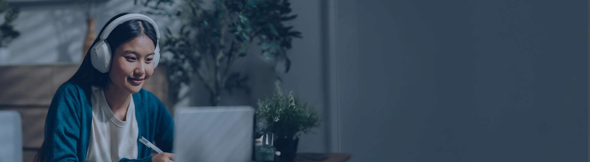 A woman wearing headphones watches a webinar on her laptop
