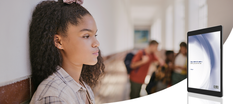 A teen girl looking upset in a school hallway while a graphic of the Social/Emotional Evaluations: Identifying Emotional Disturbance white paper is in the foreground to represent the topic